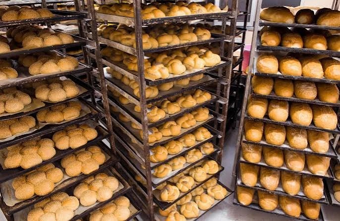 Rekken vol vers gebakken sesambollen en witte broodjes in de bakkerij